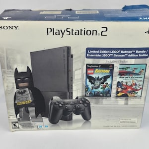 May include: A Sony PlayStation 2 Limited Edition LEGO Batman Bundle box in charcoal black. The packaging features a graphic of a LEGO Batman figure, a black console, a black controller, and game cases for LEGO Batman and Justice League: New Frontier.