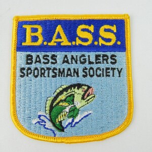 May include: A rectangular embroidered patch with a yellow border. The top section is blue with the yellow text B.A.S.S. The lower section is light blue with the black text BASS ANGLERS SPORTSMAN SOCIETY and a green and black fish jumping.