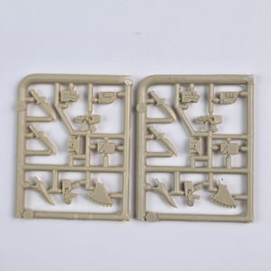 Könnte beinhalten: Zwei hellbraune Kunststoff-Modellbausatz-Gussrahmen. Jeder Gussrahmen enthält verschiedene Miniaturwaffen, darunter Messer, Äxte und Pistolen. Die Teile sind durch kleine Stege mit dem Rahmen verbunden.