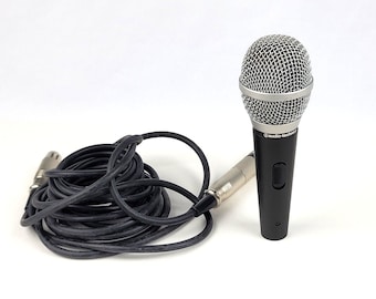 May include: A black microphone with a silver grill and a black cable. The microphone has a switch on the side and the text "audio-technica" is printed on the side.