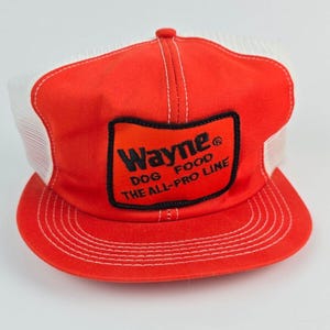 May include: Red and white trucker hat with a black patch that says "Wayne Dog Food The All-Pro Line"