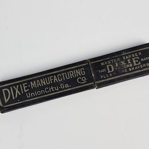 May include: A black cardboard box with gold lettering that reads "Dixie Manufacturing Co. Union City, Ga." and "Master Barber Dixie Trade Mark Razor For The Shavers".