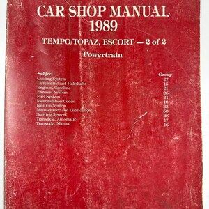 May include: A red cover for a 1989 Ford Tempo, Topaz, and Escort car shop manual. The cover has the title "CAR SHOP MANUAL 1989" and the subtitle "TEMPO/TOPAZ, ESCORT - 2 of 2 Powertrain". The cover also lists the subject and group numbers for each section of the manual.