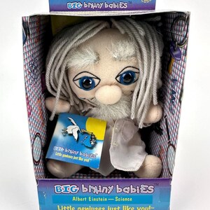 Può includere: Un giocattolo di peluche di Albert Einstein, un famoso scienziato, della collezione Big Brainy Babies. Il giocattolo indossa un camice da laboratorio bianco e ha una barba bianca e capelli grigi. La confezione dice "Little geniuses just like you!"