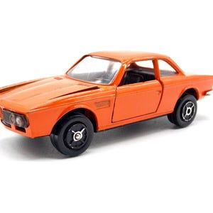 以下が含まれることがあります： 黒い車輪が付いたオレンジ色のダイキャスト製モデルカー。クラシッククーペは、詳細なフロントグリル、ヘッドライト、洗練された空力設計が特徴です。おもちゃの車は、ヴィンテージ車のミニチュアレプリカです。