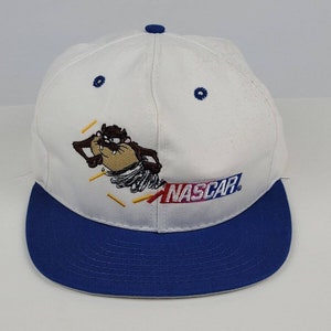May include: White and blue baseball cap with a cartoon Tasmanian Devil design and the word "NASCAR" embroidered on the front.
