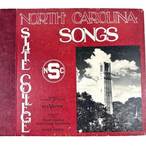 Pode incluir: Capa de álbum de vinil vintage intitulada "North Carolina Songs". A capa é vermelha com letras brancas e apresenta uma imagem em preto e branco de um edifício alto. O álbum é produzido pela RCA Victor e pela North Carolina State College Foundation.
