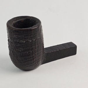 May include: A dark brown wooden pipe with a short, straight stem. The bowl of the pipe is round and has a textured surface.