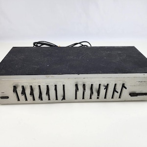 May include: A vintage Realistic Stereo Frequency Equalizer with a black top and silver face. It features multiple slider controls and a power button. The unit has a series of labeled frequency bands and a power cord.