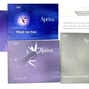 Może przedstawiać: Zbiór instrukcji i przewodników do komputera IBM Aptiva. Instrukcje są w różnych kolorach, w tym niebieskim, fioletowym i szarym. Tytuły obejmują "Unpacking", "Handbook" i "Making Your First Video Call."