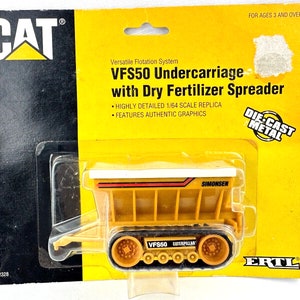 May include: A yellow die-cast metal toy model of a Caterpillar VFS50 undercarriage with a dry fertilizer spreader. The model is 1/64 scale and features authentic graphics. The packaging is yellow and black with the Caterpillar logo and the words "Die-Cast Metal".