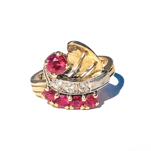 May include: A gold ring with a row of diamonds and red rubies set in a curved design.