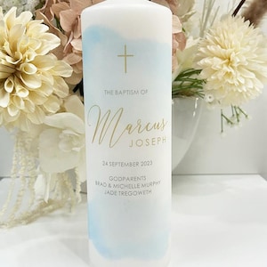May include: White baptism candle with a blue watercolour design. The candle is decorated with a gold cross and the text "The Baptism of Marcus Joseph, 24 September 2023, Godparents Brad & Michelle Murphy, Jade Tregoweth".