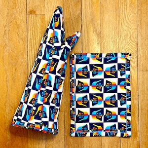 May include: A navy blue and white checkered oven mitt and matching pot holder. The design features a repeating pattern of a stylized emblem with rainbow and blue accents. The edges of the pot holder are trimmed with a blue border.