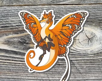 May include: A sticker of an orange and black butterfly dragon with a curled tail and wings spread out. The dragon has a black and orange body with a white face and orange eyes.