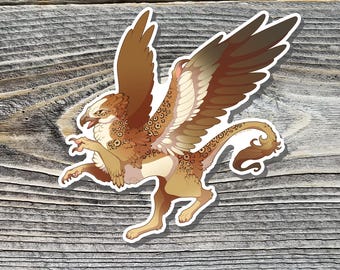 May include: A sticker featuring a griffin, a mythical creature with the body of a lion and the head and wings of an eagle. The griffin is depicted in shades of brown, tan, and cream, with detailed feather and scale patterns. The sticker has a white border.