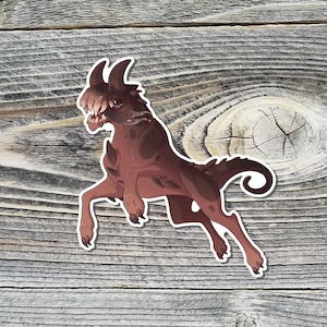 Puede incluir: Una pegatina con una ilustración estilizada de una criatura marrón con cuernos en una pose dinámica. La criatura tiene una cara detallada con dientes visibles y una melena fluida. La pegatina está sobre un fondo de madera rústica.