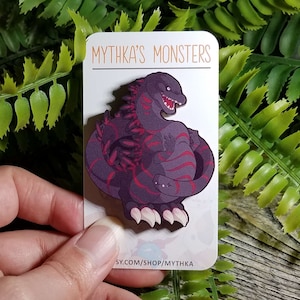 May include: A purple and red cartoon monster with a toothy grin, on a white card with the text "Mythka's Monsters" and a website address.