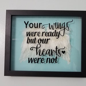 May include: A framed shadow box with a blue background and white feathers. The text "Your wings were ready but our hearts were not" is printed in black.