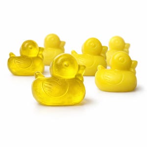 May include: Six yellow rubber duck toys are arranged on a white background. The ducks are a bright yellow color and have a classic design with a round body, a beak, and wings. The ducks are made of a translucent material.