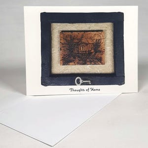 Wenskaart getiteld "Thoughts of Home" - tekening van een huis onder volle maan en antieke loper - ideaal om een bericht naar een geliefde te sturen