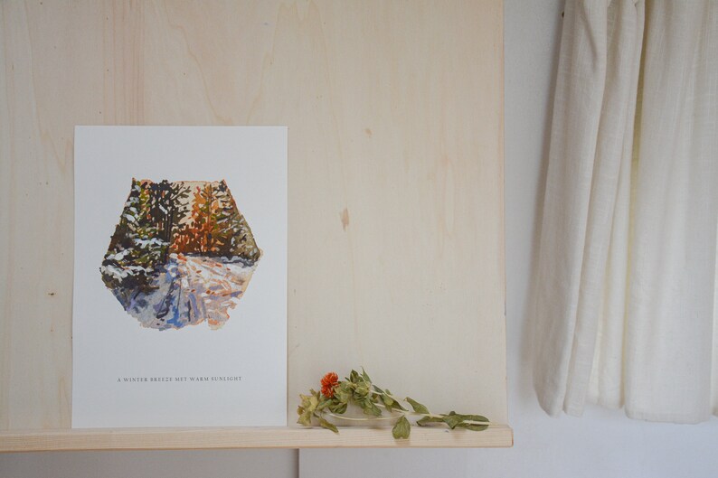 May include: A white print with a watercolor painting of a snowy forest path. The text "A winter breeze but warm sunlight" is at the bottom of the print.