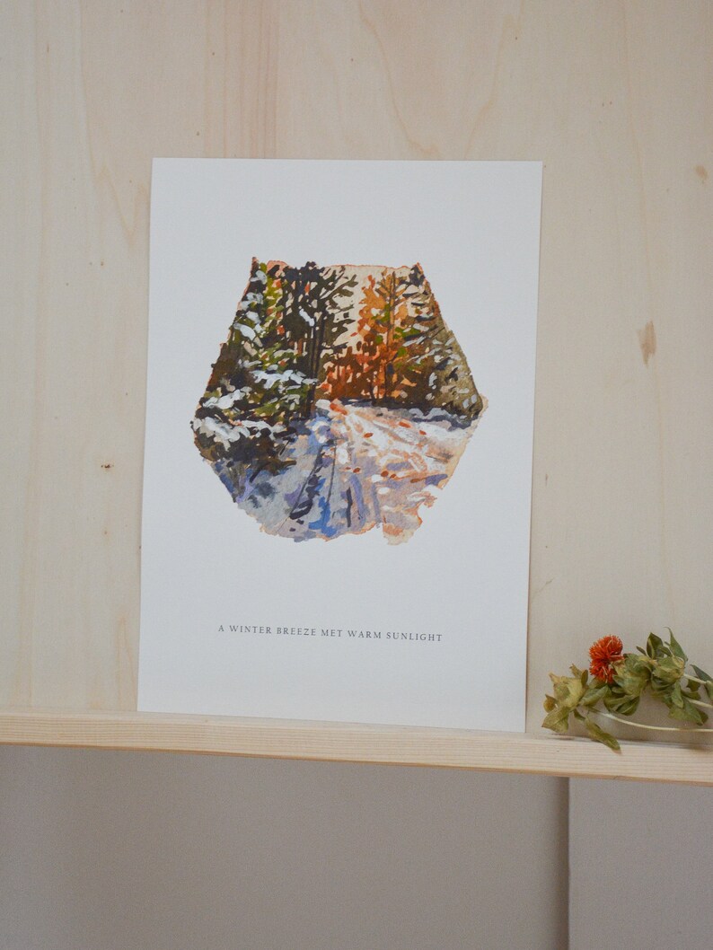 May include: A watercolor painting of a snowy forest path with a warm, golden light shining through the trees. The text "A winter breeze met warm sunlight" is printed below the image.