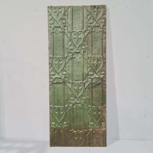 Puede incluir: Una teja de techo de estaño verde con un patrón en relieve de corazones y espirales. La teja tiene un aspecto desgastado y es perfecta para agregar un toque vintage a cualquier habitación.