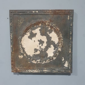 May include: A square, dark grey metal tile with a white, circular design in the centre. The white design has a distressed, chipped look, giving the tile a vintage feel.