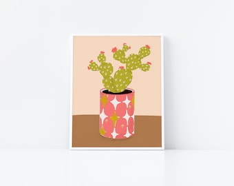 May include: A green cactus with pink flowers in a pink and white patterned pot with gold stars. The pot is sitting on a brown surface.