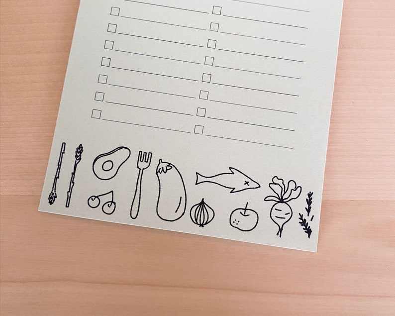 Op de afbeelding: Een checklist met een lege ruimte om te schrijven en een rij zwart-wit illustraties van verschillende voedingsmiddelen, waaronder een avocado, een vork, een aubergine, een ui, een appel, een vis, een radijs en takjes rozemarijn.