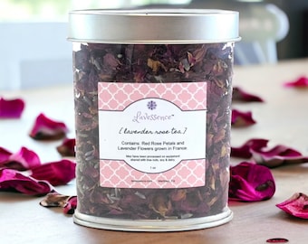 May include: A clear cylindrical container with a silver lid filled with dried rose petals and lavender flowers. A pink label reads "Lavessence {lavender rose tea}" with text about the ingredients. The container is 28 grams.