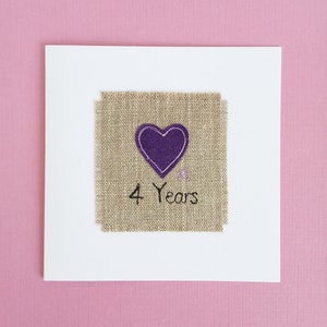 May include: A white card with a burlap square featuring a purple heart and the text "4 Years".