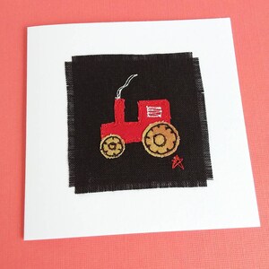 Puede incluir: Un tractor rojo de tela con ruedas negras y una estrella blanca sobre un fondo de tela negro.