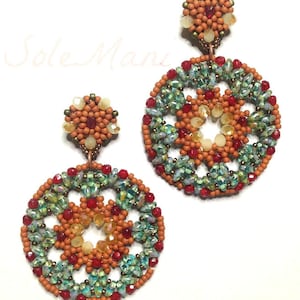 Könnte beinhalten: Handgefertigte Perlenohrringe mit kreisförmigem Design, das orange, rote und grüne Perlen enthält. Die Ohrringe haben eine kleine, runde Oberseite und eine größere, kreisförmige Unterseite. Die komplizierte Perlenarbeit erzeugt ein detailliertes, auffälliges Muster.