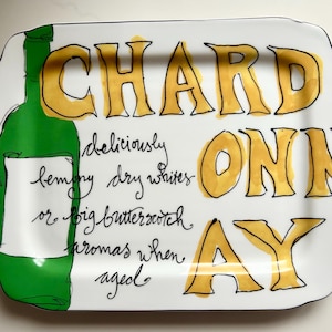 May include: White rectangular serving platter with a black border. The platter features the word "CHARDONNAY" in yellow block letters. A green wine bottle illustration is on the left. Text describes the wine's characteristics.