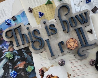 May include: A wooden sign with the text "This is how I roll" in black lettering. The sign is on a table with dice and other game pieces.