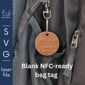 Könnte beinhalten: Ein runder, holzfarbener Gepäckanhänger mit silberfarbenem Metallring und Karabinerhaken. Auf dem Anhänger steht "Blank NFC-ready bag tag". Der Anhänger hängt an einem schwarzen Rucksack.