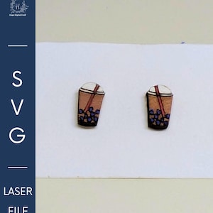 May include: Two wooden earrings shaped like bubble tea cups. The cups are brown with a white top, a brown straw, and purple boba. The image also includes the text "SVG LASER FILE".