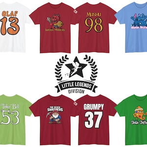 May include: A collection of colorful t-shirts featuring cartoon characters and numbers. Designs include a snowman, Olaf with the number 13, Mushu with 98, Stitch with 626, and others. The shirts are labeled "Little Legends Division".