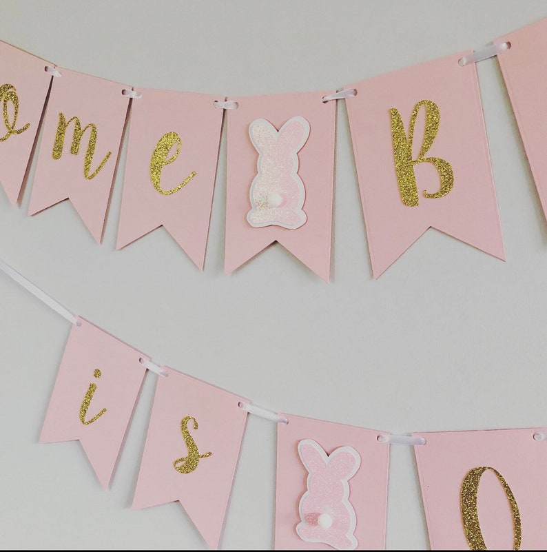 Op de afbeelding: Roze en gouden banner met de woorden "Come is one" en konijnen uitsnijdingen.