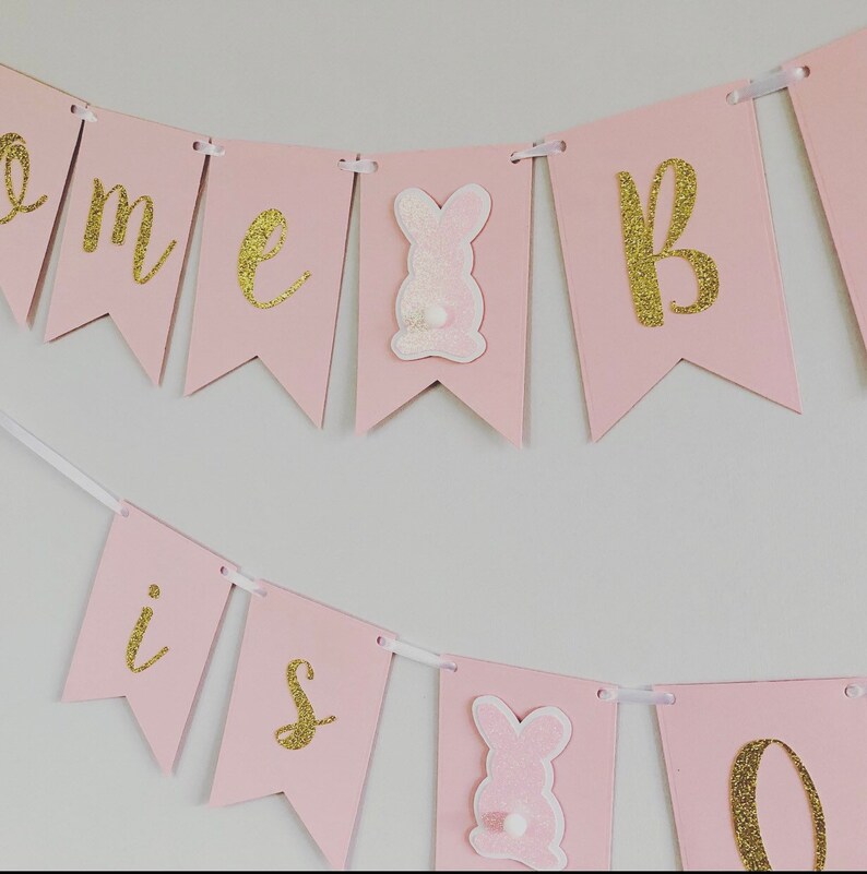 Op de afbeelding: Roze en gouden banner met de woorden "Come is one" en konijnen uitsnijdingen.