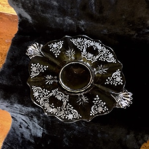 May include: A clear glass serving dish with a scalloped edge and intricate etched floral designs. The dish has two handles and is perfect for serving snacks or desserts.