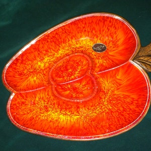 May include: A red and orange ceramic apple-shaped serving dish with two separate bowls. The dish has a brown wooden stem and leaf.