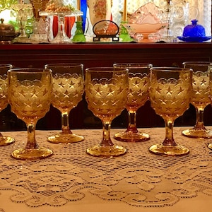 May include: Set of ten amber glass wine glasses with a starburst pattern. The glasses have a scalloped rim and a short stem.