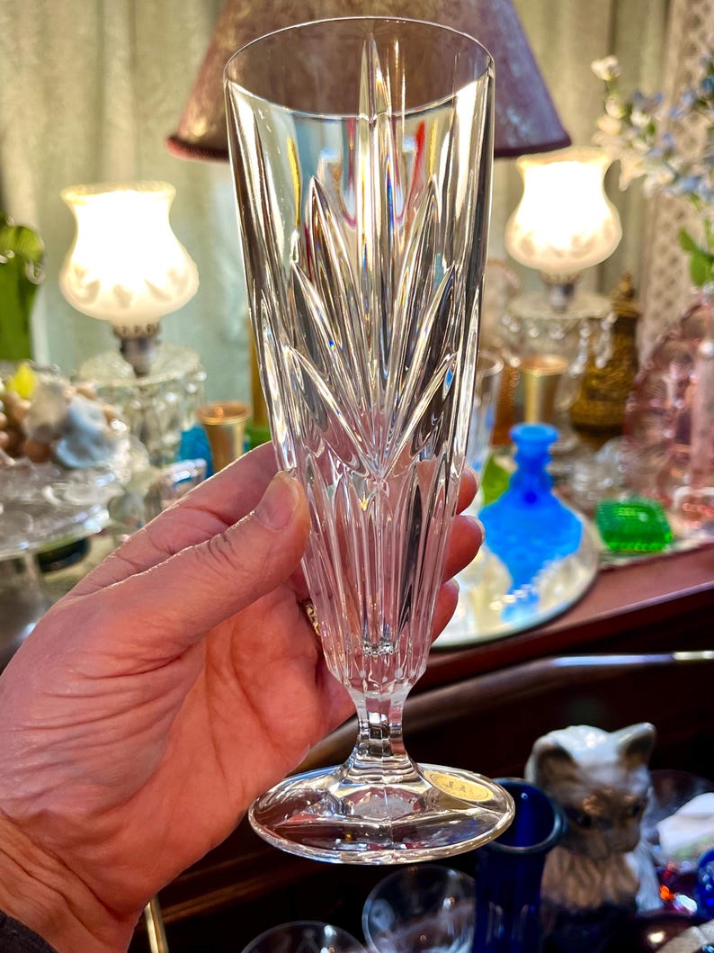 Peut inclure: Un fl&ucirc;te &agrave; champagne en cristal transparent avec un motif grav&eacute; d&eacute;taill&eacute;. Le verre a une longue tige et une base large et circulaire. Le motif grav&eacute; pr&eacute;sente des lignes verticales et des formes de feuilles, cr&eacute;ant un aspect textur&eacute;.