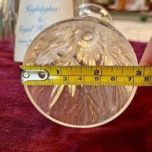 Peut inclure: Objet rond en verre cristal transparent avec un motif en &eacute;toile, mesurant environ 7,6 cm de diam&egrave;tre. Un m&egrave;tre ruban jaune est plac&eacute; sur l'objet. Le texte "Highlights & Royal H" est visible en arri&egrave;re-plan.