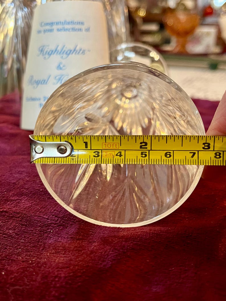 Peut inclure: Objet rond en verre cristal transparent avec un motif en &eacute;toile, mesurant environ 7,6 cm de diam&egrave;tre. Un m&egrave;tre ruban jaune est plac&eacute; sur l'objet. Le texte "Highlights & Royal H" est visible en arri&egrave;re-plan.