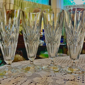 Peut inclure: Quatre fl&ucirc;tes &agrave; champagne en cristal transparent avec un motif grav&eacute;. Les fl&ucirc;tes sont hautes et fines, avec une base ronde. Chaque verre a un autocollant dor&eacute; sur la base. Id&eacute;al pour les c&eacute;l&eacute;brations.
