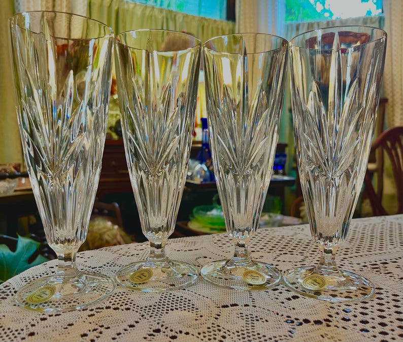 Peut inclure: Quatre fl&ucirc;tes &agrave; champagne en cristal transparent avec un motif grav&eacute;. Les fl&ucirc;tes sont hautes et fines, avec une base ronde. Chaque verre a un autocollant dor&eacute; sur la base. Id&eacute;al pour les c&eacute;l&eacute;brations.